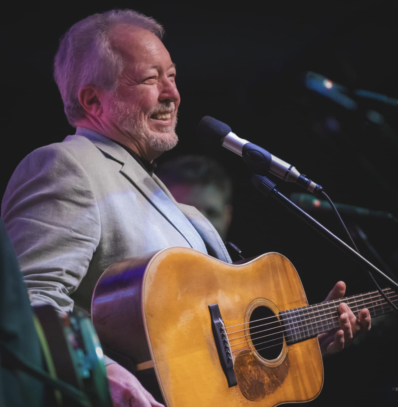 Russell Moore smiling on stage with his acoustic guitar
